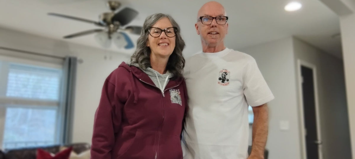 A couple in a He Has Triumphed hoodie and a Joy of the Lord tee, front prints