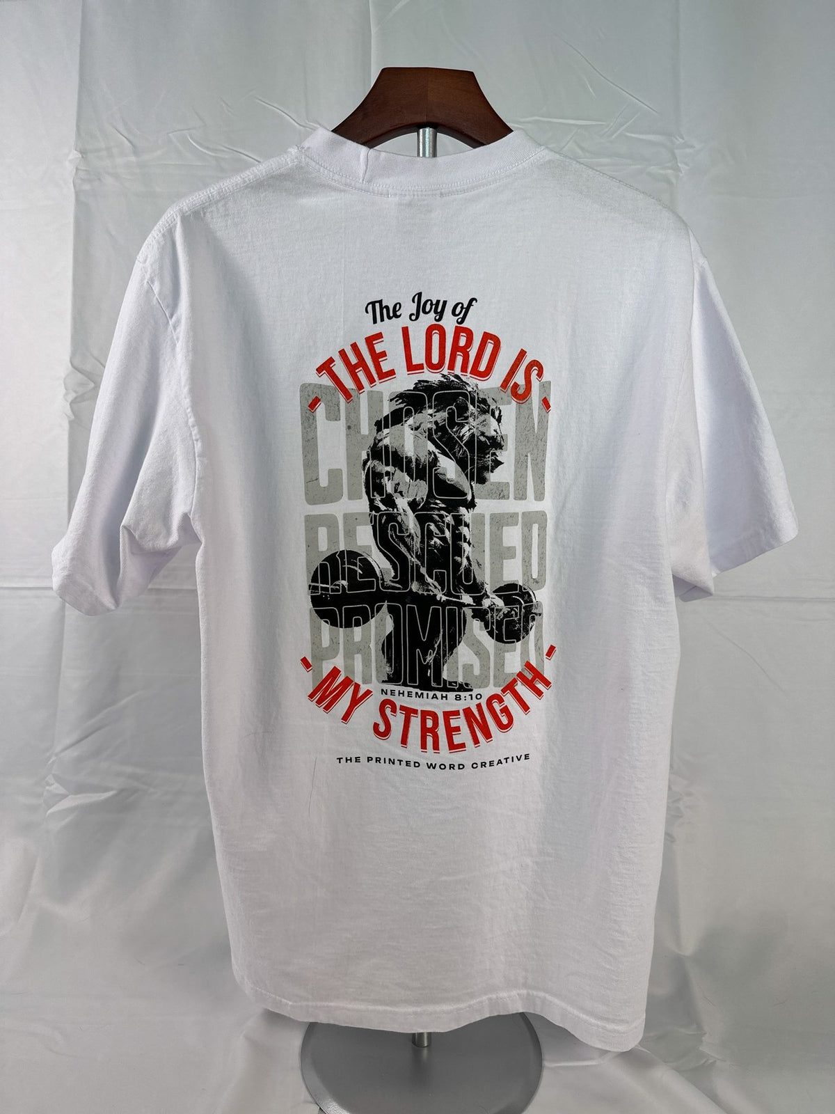 The Joy of the Lord on a white tee, on a hanger
